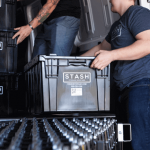 two men loading black Stash Storage boxes into moving truck